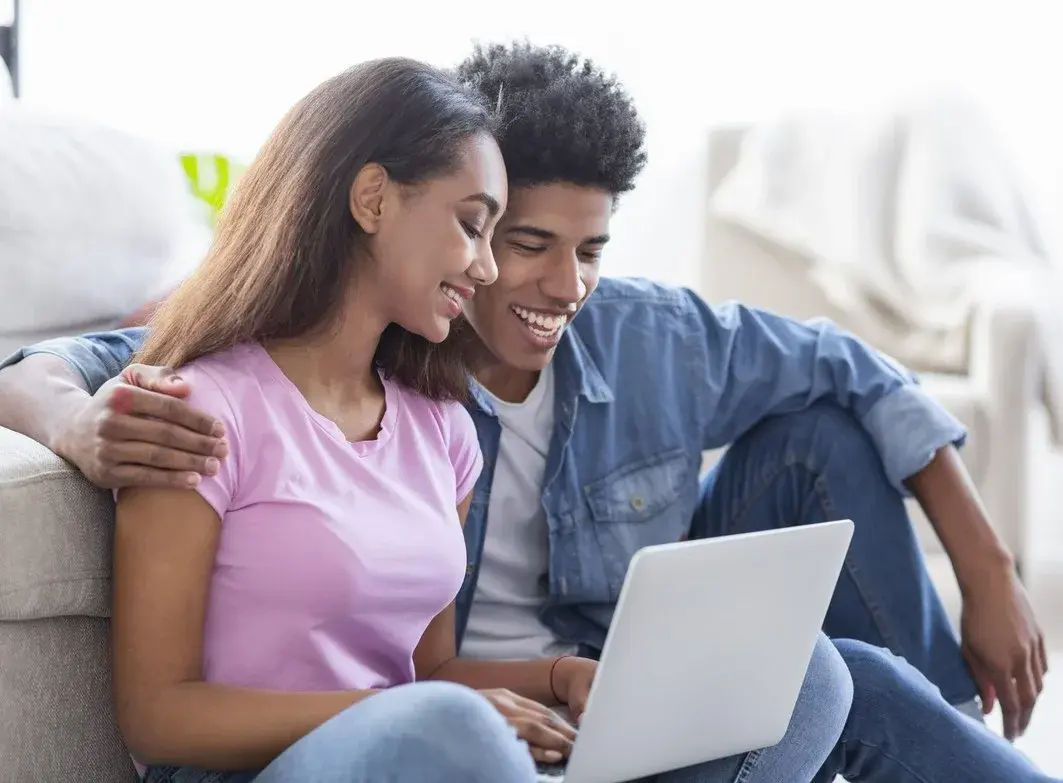 A young couple smiling together while looking at a laptop