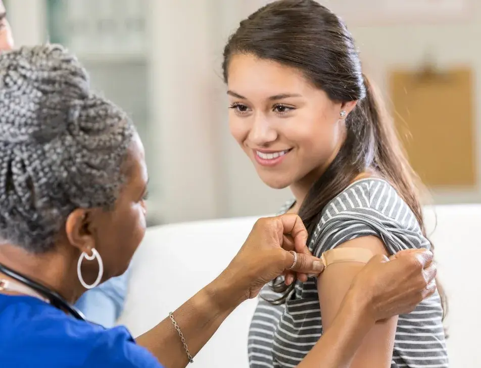 A healthcare professional applying a plaster after a student's vaccination