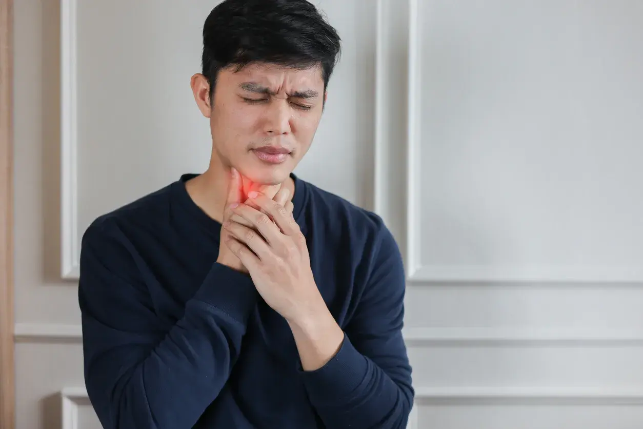 A man holding his throat in discomfort